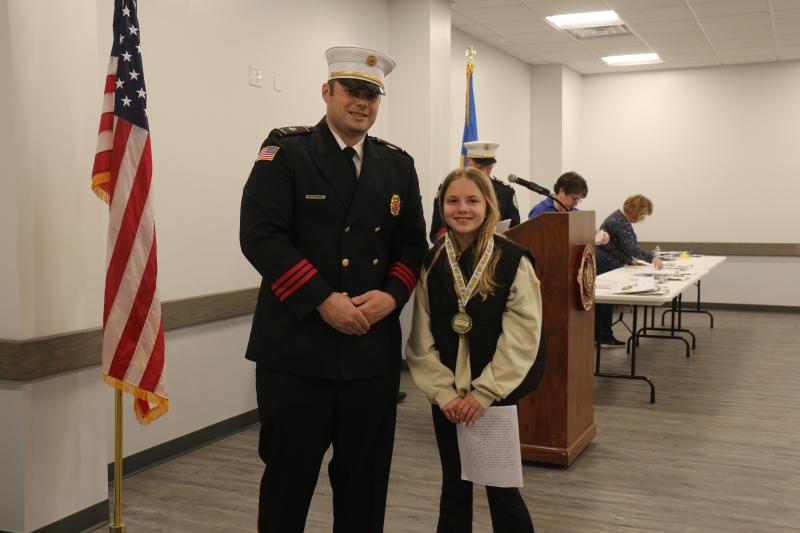 Delmarva Christian fifth-grader Margot Eden is congratulated on her first-place win by MFD President Brian Reynolds Jr.